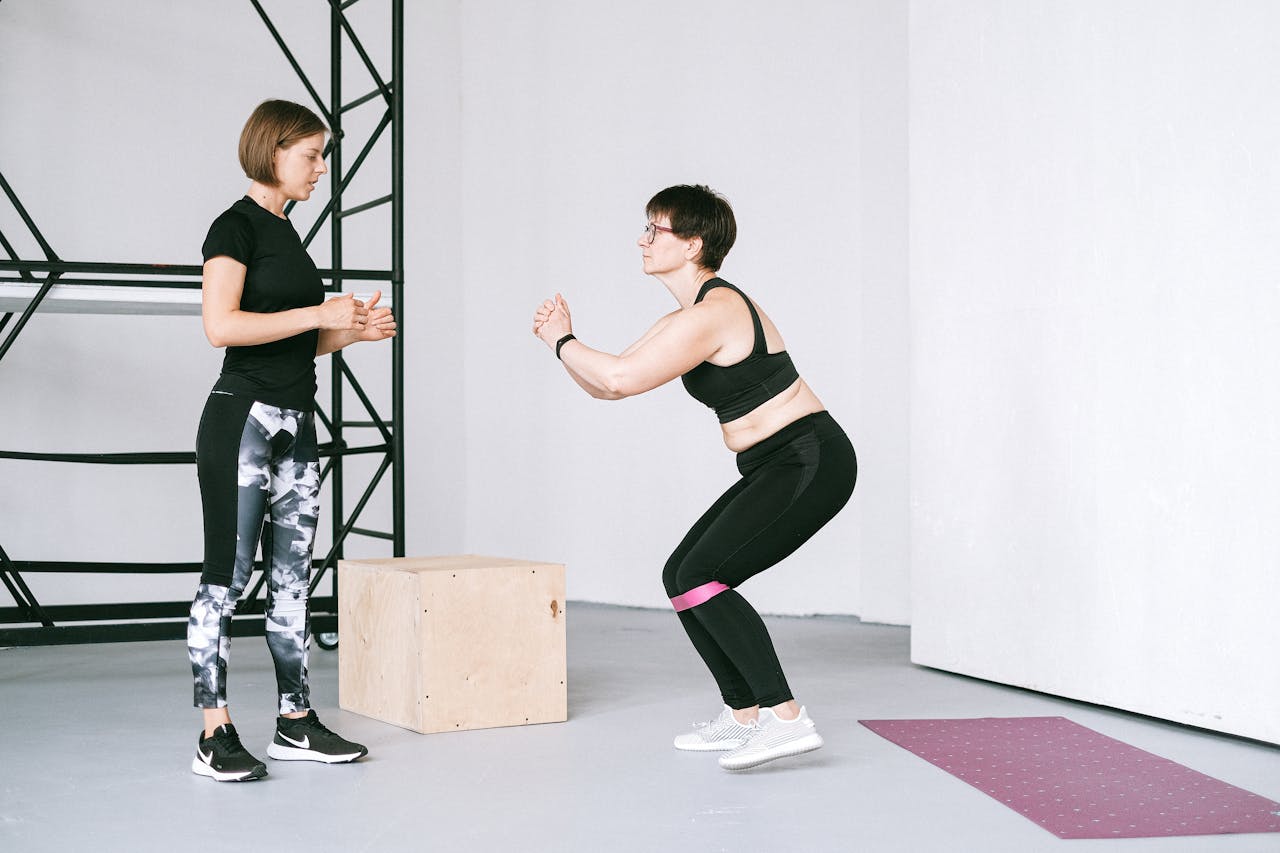 Two women engaging in a fitness workout with resistance bands at an indoor gym.