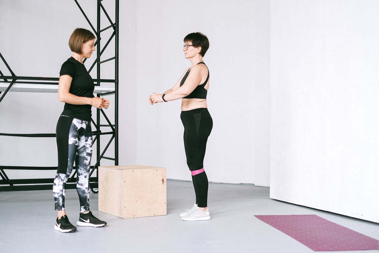 Two women exercising indoors, focusing on fitness and healthy lifestyle with guidance.